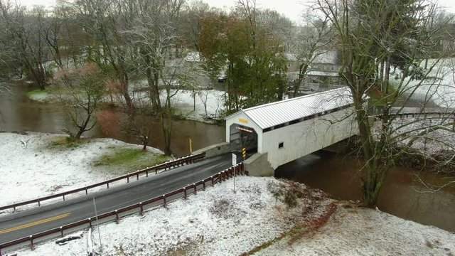 Covered bridge in Pennsylvania with first snow covering the landscape, aerial push shot