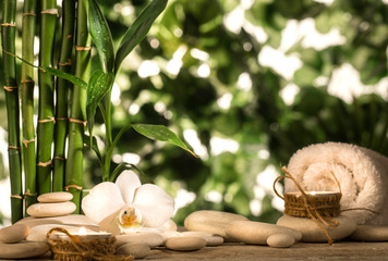 Grean bamboo leaves, white orchid, towel and candles over zen stones on tropical leaves background