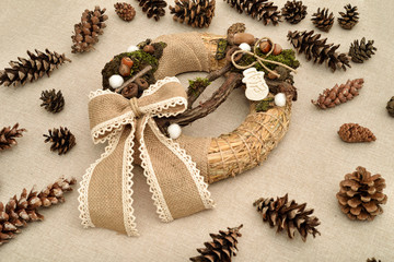 Decorated handmade Christmas wreath and pine cones on the table              