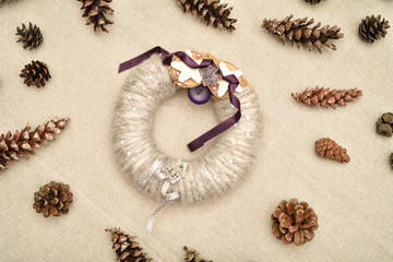 Decorated handmade Christmas wreath and pine cones on the table. Top view.      