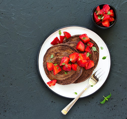 Chocolate pancakes with strawberries and strawberry sauce.