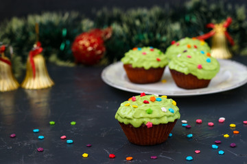 Homemade cupcakes covered with cream and pastry decorations are located on a festive dark background