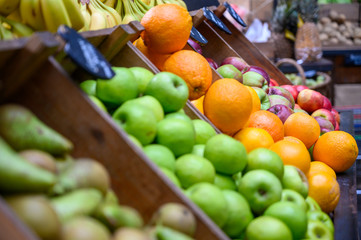 Apples, oranges, pears and bananas on display and ready for sale at a fruit and veg stall in Borough Market, London