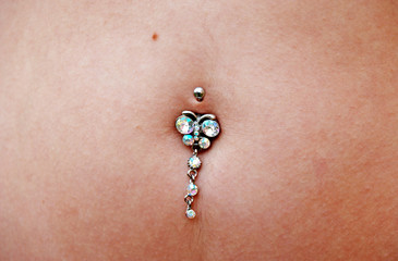  Piercing in the belly. Umbigo feminino com brinco de pedras preciosas anexado. Umbigo com brinco anexado para adorno.