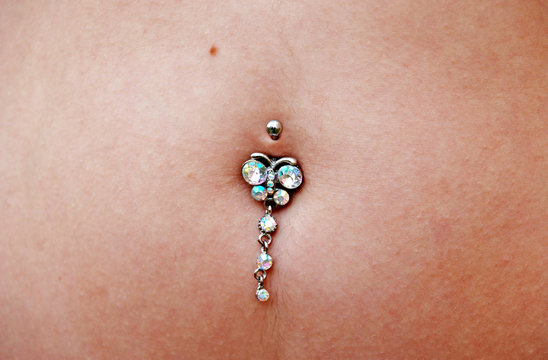  Piercing in the belly. Umbigo feminino com brinco de pedras preciosas anexado. Umbigo com brinco anexado para adorno.