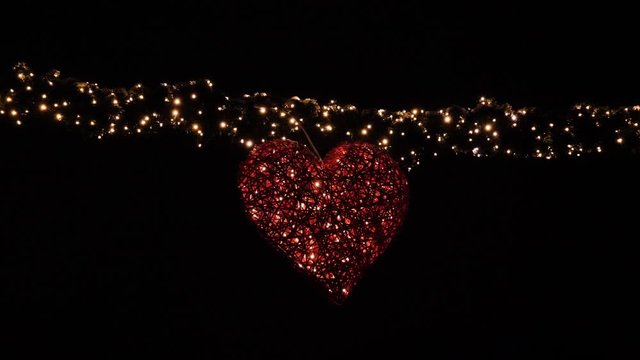 Heart shaped banner with lights to celebrate Christmas, New Year or Valentines Day - night with black background