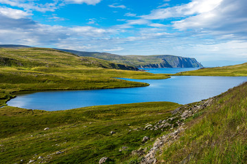 Fototapeta na wymiar Storvatnet lake in Mageroya island. The coastline of the Barents Sea in Nord Cape direction is at background. Nordkapp Municipality in Norwegian Finnmark county.