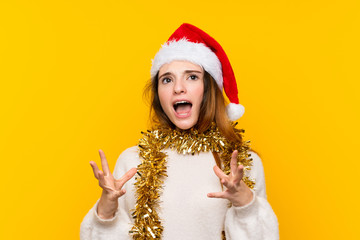 Girl with christmas hat over isolated yellow background unhappy and frustrated with something