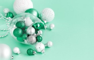 Christmas baubles in a wine glass on a light green background