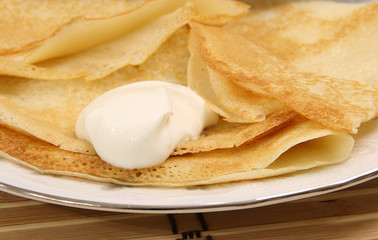 Golden homemade baked pancakes and sour cream on a plate