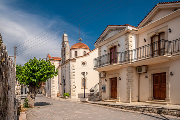 Fototapeta na wymiar Street with yellow houses and a church in a Cretan village