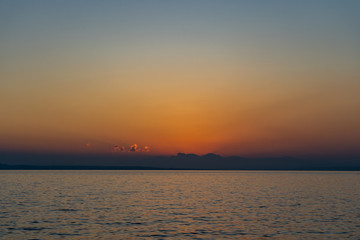 Naklejka na ściany i meble Sun is about to rise above clouds on sea horizon in Ioniean sea, view from Zakynthos island