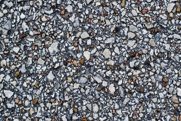 Gravel pieces mixed with asphalt in a paved road close up. Abstract full frame background.