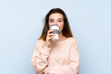 Young brunette girl over isolated blue background holding and drinking a coffee to take away