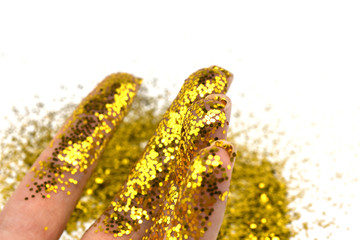 Hand in golden glitter. Golden fingers. Female hand isolated on white background with sparkles. Festive concept.