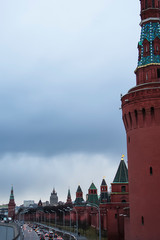 Obraz premium Kremlin wall, red brick fortress; traffic along the embankment of Moscow River; rainy weather, evening; Russia