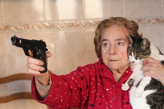 Angry Senior Woman Protecting Her Cat With A Gun 