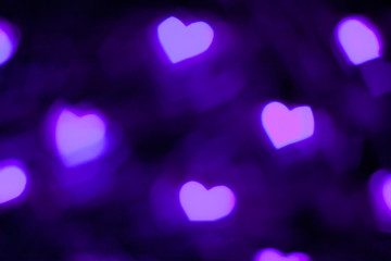 Purple and violet lights makes hears shape bokeh. Dark background concept