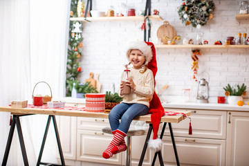 little girl in pajamas and Santa hat drinking cocoa milk