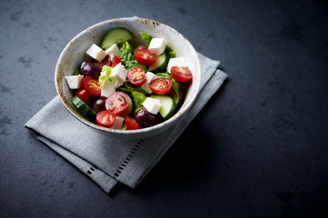 Salad with Kalamata Olives, Cucumber Cherry Tomatoes and Feta Cheese on black Stone Background. Healthy Snack Idea. Copy space. 