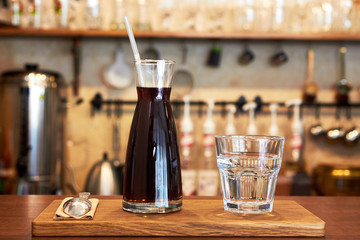 Fototapeta na wymiar Glass with cold brew coffee and glass with water on a coffee shop counter