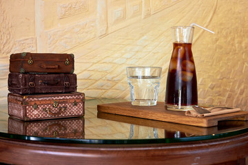 Glass with cold brew coffee and glass with water on table at coffee shop