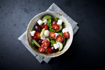 Salad with Kalamata Olives, Cucumber Cherry Tomatoes and Feta Cheese on black Stone Background. Healthy Snack Idea. Top view. Copy space. 