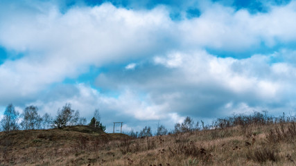 Empty swing on a hill in the middle of a field on blue sky background.