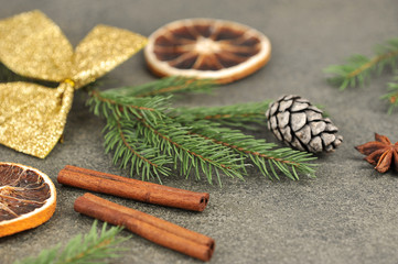 Obraz na płótnie Canvas Christmas composition: Almonds, anise, pine cone, spruce branch, orange, cinnamon sticks on a dark background. Close-up.