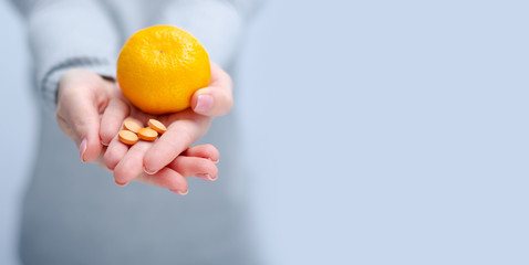 Woman holding tangerine and vitamin C, medecine, health care on gray light background, space for text - obrazy, fototapety, plakaty