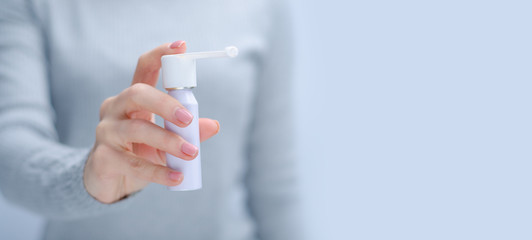 Woman holding throat spray medicine health care on gray light background, space for text