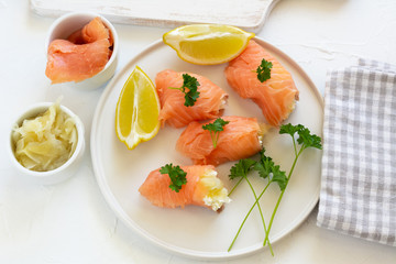 Slices of smoked salmon wrapped with cottage cheese and marinated ginger. Party snack.