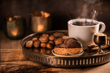 Delicious crunchy nut biscuits with chocolate glaze and a steaming cup of tea on a tarnished silver tray. Cozy Christmas atmosphere. Christmas concept/Afternoon tea.