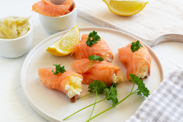 Slices of smoked salmon wrapped with cottage cheese and marinated ginger. Party snack.