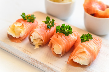 Slices of smoked salmon wrapped with cottage cheese and marinated ginger. Party snack.