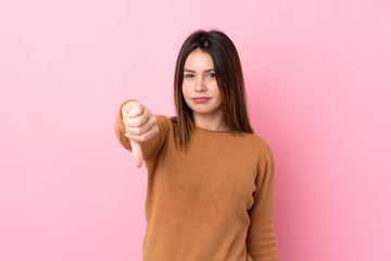 Young woman over isolated pink background showing thumb down with negative expression