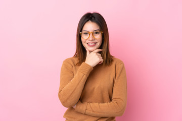 Young woman over isolated pink background with glasses and smiling