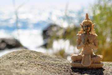 Buddha figurine on a stone on a background of the sea