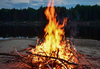 Bonfire on the river in the evening in the summer. On the Sunset