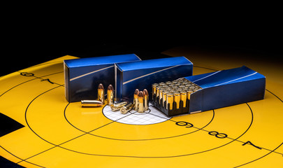 Cartridges in a blue box on a background of a yellow target. 9 mm cartridges for firearms.