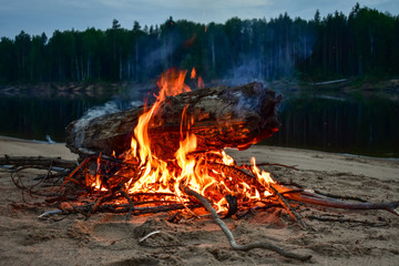 Bonfire on the river in the evening in the summer. On the Sunset