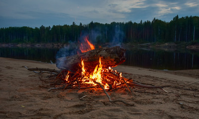 Bonfire on the river in the evening in the summer. On the Sunset