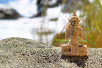 Buddha figurine on a stone on a background of the sea