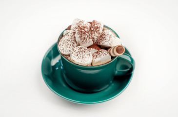 Cappuccino with marshmallows in a green mug on a white background