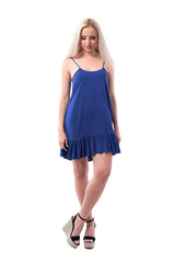 Pretty blonde girl in elegant summer dress looking down smiling and having happy thoughts. Full body isolated on white background. 