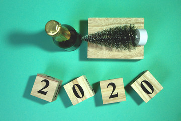 New Year composition with bottle champagne and decorative new year tree. Wooden cube block building the word 2020.