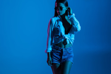 Young sexy woman standing isolated on blue light background