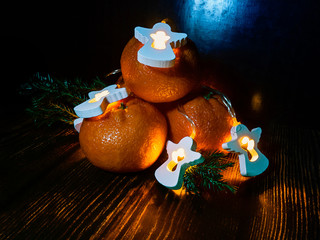 Merry Christmas. Tangerines and garland with angels on a wooden surface.