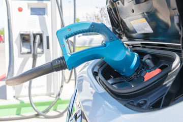 Electric car plugged in to charge battery at a charging station