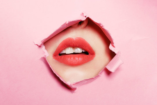 Big beautiful lips, beauty salon, lip enhancement, Botox. Beautiful teeth, dentistry. Pink background, girl's face through torn cardboard.